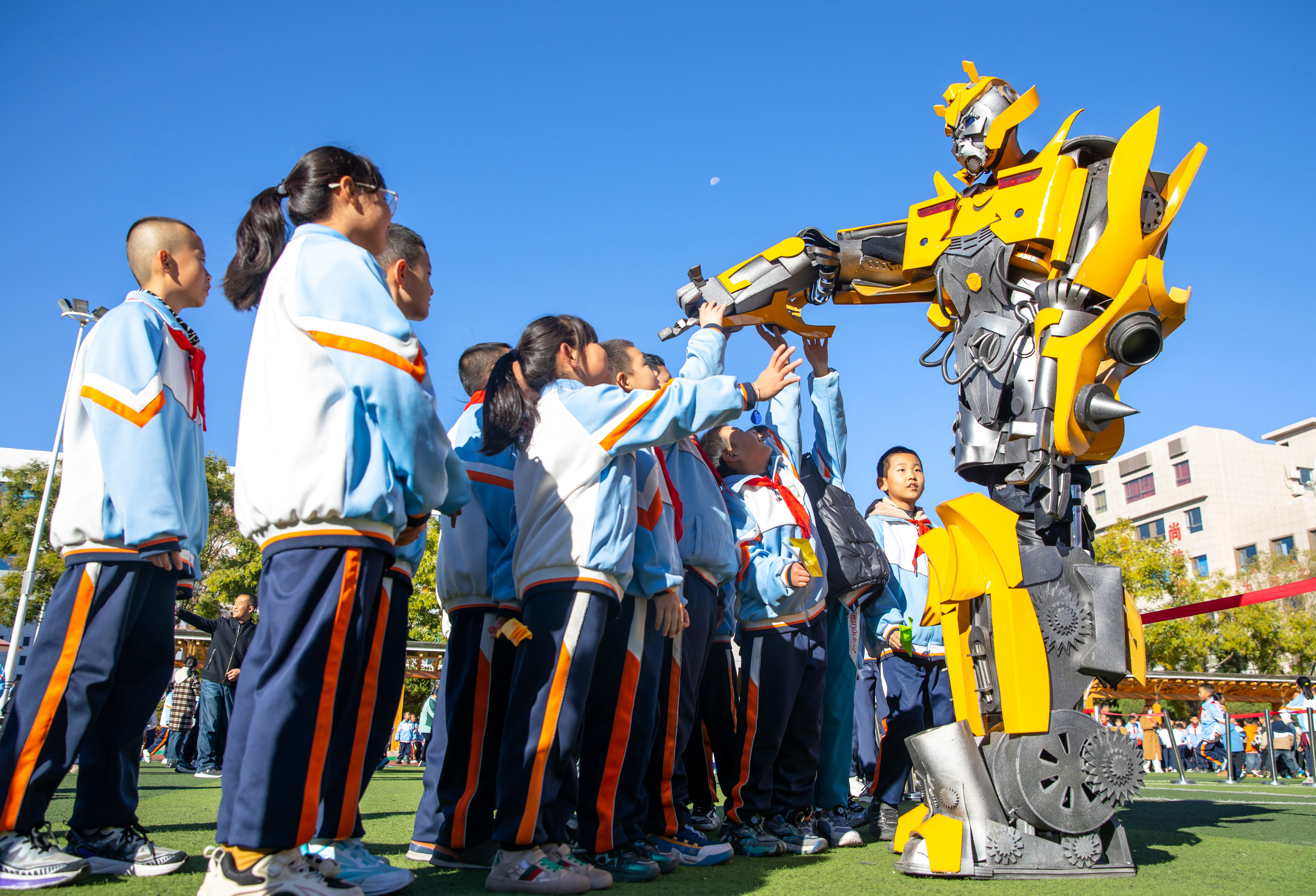 2024年10月22日，在甘肅省張掖市甘州區(qū)北街街小學科技大篷車嘉年華活動上，學生與“大黃蜂”機器人互動。楊瀟 攝.jpg